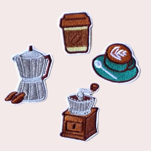 Peut inclure: Cinq patchs brodés thermocollants représentant des motifs sur le thème du café : une tasse à café marron, une tasse à café verte avec une cuillère, une cafetière argentée, un moulin à café marron et un grain de café marron.