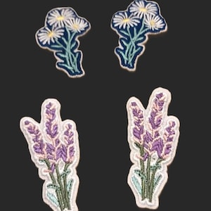 May include: Four embroidered iron-on patches featuring floral designs. Two patches feature white daisies with blue stems and leaves. Two patches feature purple lavender flowers with green stems and leaves.