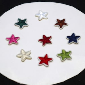May include: Ten embroidered felt star patches in various colours, including red, green, blue, white, and brown. The stars are arranged in a circle on a white background.