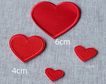 May include: Four red heart-shaped fabric patches of varying sizes. The largest heart is labelled 6cm, the medium heart is labelled 4cm, the small heart is labelled 2.5cm, and the smallest heart is labelled 2cm. Each patch has a stitched border.