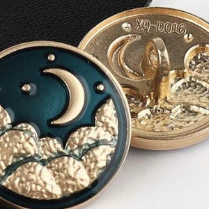 May include: A pair of gold-tone metal buttons featuring a crescent moon and star design. The front of the button has a dark green enamel background with gold-tone crescent moon and stars. The reverse of the button is plain gold-tone metal with the text "XQ-D016".