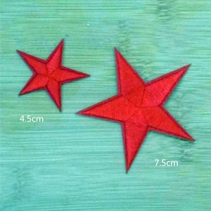 May include: Two red felt star shapes on a turquoise background. The larger star is 7.5 cm wide and the smaller star is 4.5 cm wide.