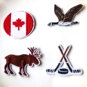 May include: Four embroidered iron-on patches featuring Canadian themes: a Canadian flag, a moose, a hockey stick and puck, and a flying Canada goose.