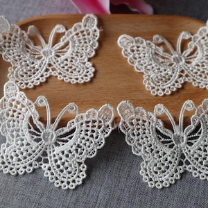 May include: Four white lace butterfly appliques. The appliques are delicate and intricate, with a detailed design. They are perfect for adding a touch of elegance to any project.