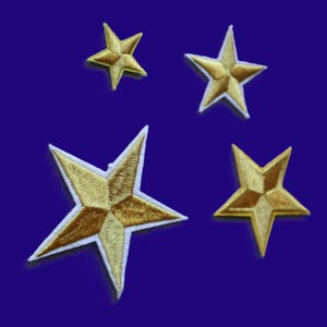 May include: Four embroidered star patches in varying sizes, each featuring a metallic gold thread finish with a distinct five-pointed shape and a white border outline. The stars are arranged in a scattered formation against a solid dark blue background.