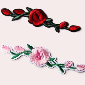 May include: Two embroidered flower patches, one with red roses and one with pink flowers. Both patches have green stems and leaves.