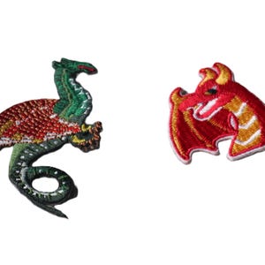May include: Two embroidered patches featuring dragon designs. One patch depicts a full-bodied green dragon with a red wing and a curled tail. The second patch shows a red dragon head with yellow accents and a small wing, both with white borders.