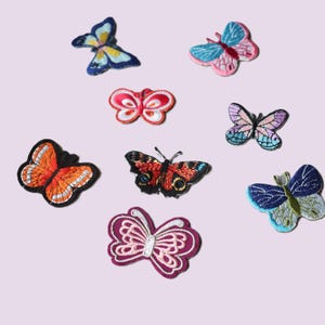 Peut inclure: Un assortiment de patchs papillon brodés aux couleurs variées, dont le bleu, le rose, l'orange et le violet. Chaque patch présente des coutures détaillées et des motifs d'ailes uniques. Ces patchs décoratifs sont parfaits pour ajouter du style aux vêtements ou accessoires.
