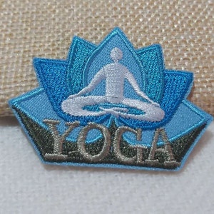 May include: A blue and white embroidered patch with a lotus flower and a person in a yoga pose. The word "YOGA" is embroidered in gray below the figure.