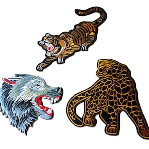 May include: Three embroidered iron-on patches featuring a wolf, a tiger, and a jaguar. The wolf is blue and gray, the tiger is orange and black, and the jaguar is black and gold.