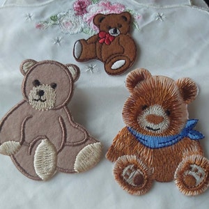 May include: Three embroidered teddy bear patches. One is brown with a red bow, one is light brown, and one is brown with a blue scarf.
