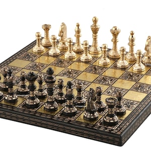 May include: A chess set featuring a square board with alternating black and metallic gold squares, decorated with intricate patterns. The pieces are divided into two sets: one set is finished in a polished metallic gold, and the other is black with gold accents.