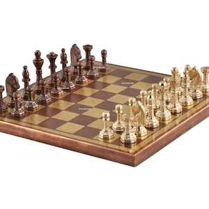 May include: A chess set featuring a square board with alternating dark copper and light gold squares. One side has dark copper-toned metal chess pieces, while the opposing side features polished gold-toned metal chess pieces in standard designs.