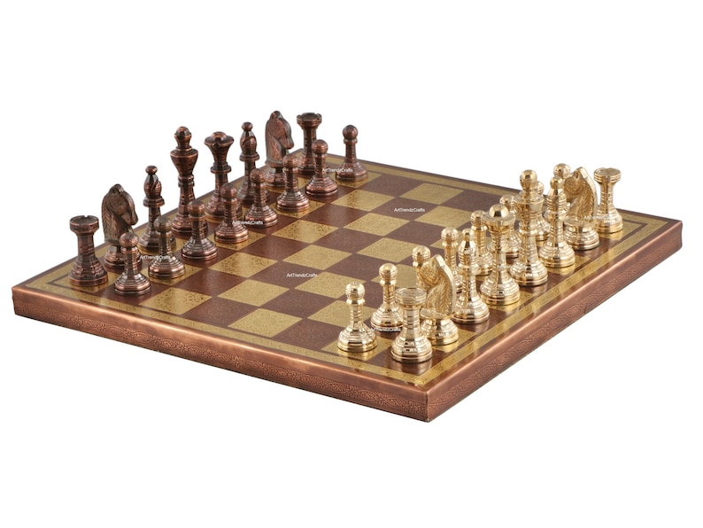 May include: A chess set featuring a square board with alternating dark copper and light gold squares. One side has dark copper-toned metal chess pieces, while the opposing side features polished gold-toned metal chess pieces in standard designs.