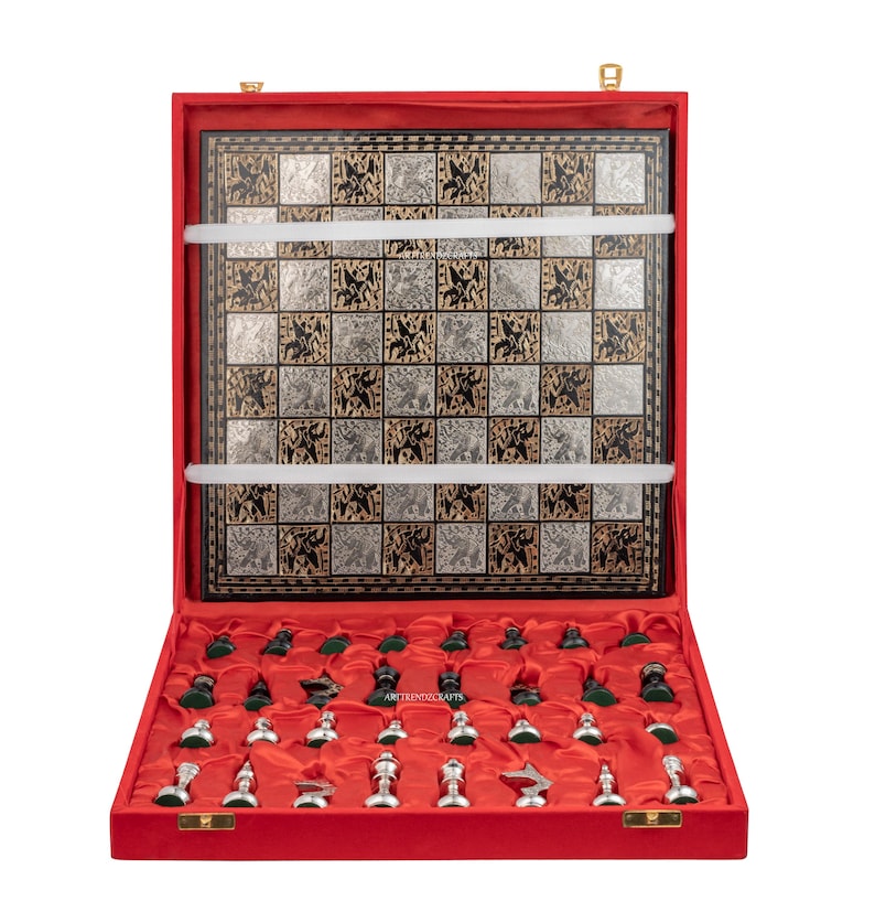 May include: A chess set in a red velvet-lined case featuring a square board with alternating silver and black squares decorated with intricate etched animal figures. The set includes a collection of silver and dark green chess pieces.