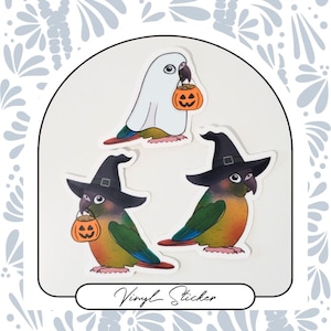 May include: Three vinyl stickers featuring a white parakeet with a pumpkin, a green parakeet with a witch hat and pumpkin, and a green parakeet with a witch hat. The stickers are on a white background.