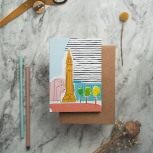May include: A card with a colorful illustration of Big Ben, a famous landmark in London, England. The card is on a brown envelope.
