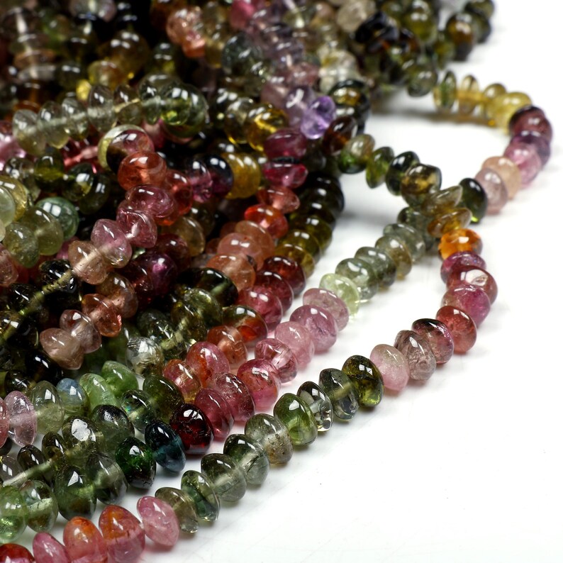 May include: A strand of multi-colored gemstone beads. The beads are faceted and have a smooth, polished finish. The colors of the beads include green, pink, red, and brown.
