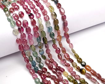 May include: A strand of multi-colored gemstone beads, featuring shades of pink, green, blue, and brown. The beads are oval-shaped and have a smooth, polished finish.