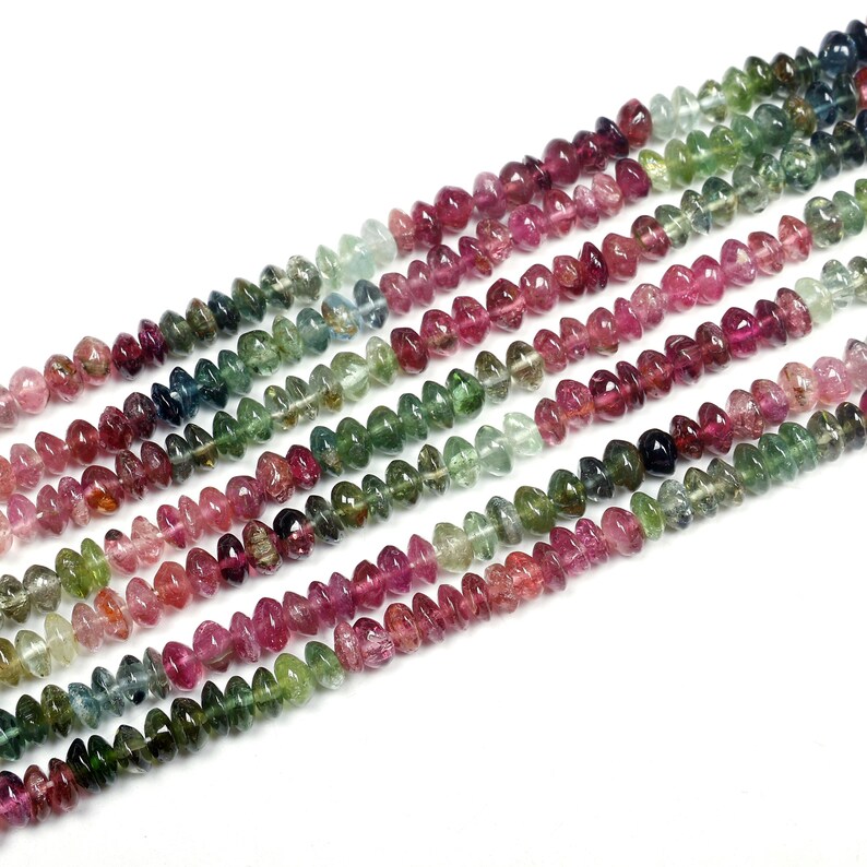 May include: A strand of multi-colored gemstone beads. The beads are faceted and have a teardrop shape. The colors of the beads are pink, green, and blue.