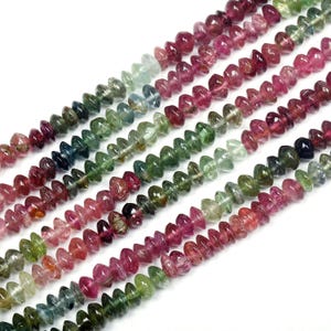 May include: A strand of multi-colored gemstone beads. The beads are faceted and have a teardrop shape. The colors of the beads are pink, green, blue, and black.