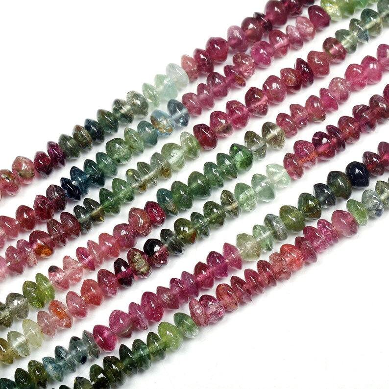 May include: A strand of multi-colored gemstone beads. The beads are faceted and have a teardrop shape. The colors of the beads are pink, green, blue, and black.