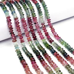 May include: Multicolored gemstone beads in shades of pink, green, and blue. The beads are faceted and have a slightly elongated shape. The beads are strung on a thread and are ready to be used for jewelry making.