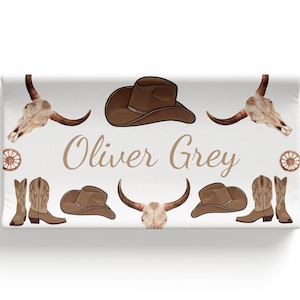 May include: A white background with a brown cowboy hat, two pairs of brown cowboy boots, two brown steer skulls, and two brown wagon wheels. The text "Oliver Grey" is written in brown cursive.