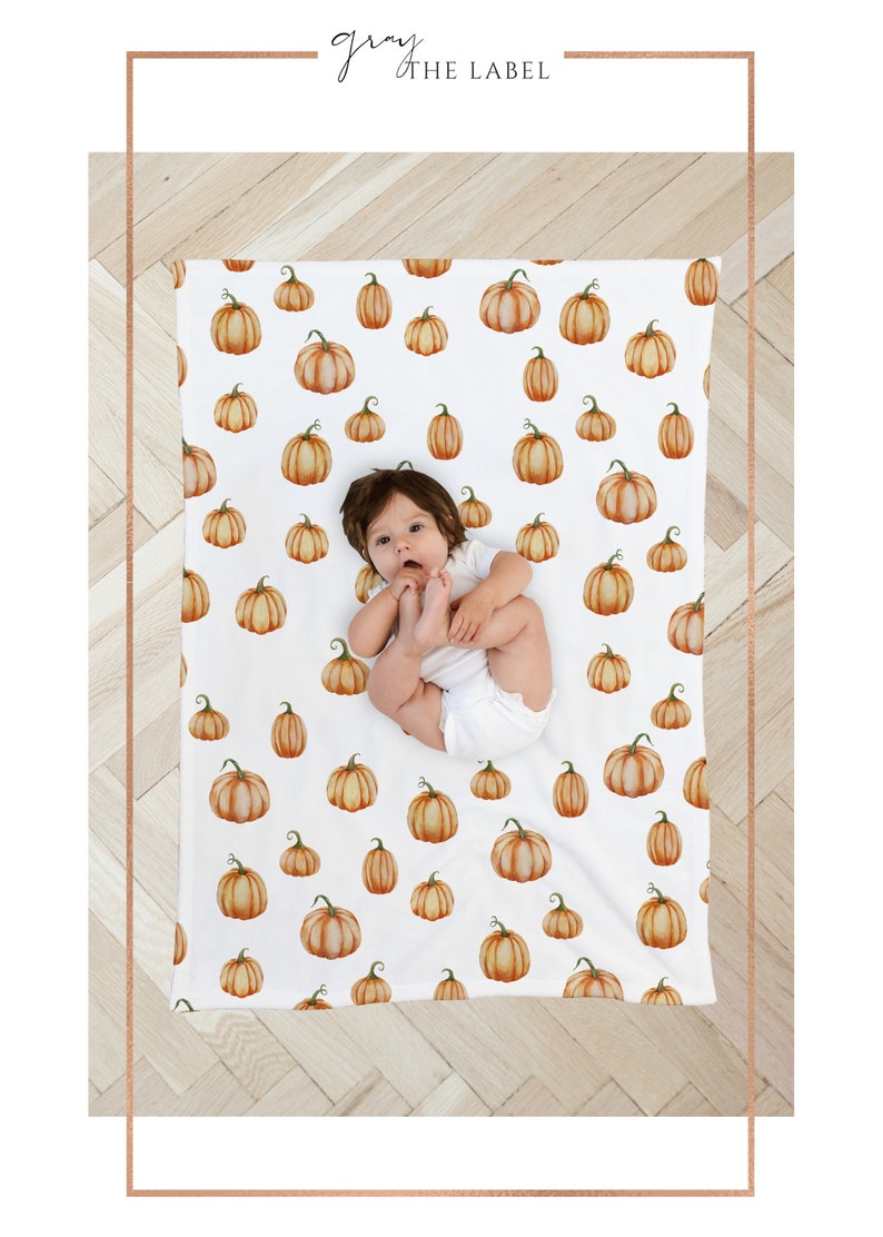 May include: A white baby blanket with a pumpkin pattern. The blanket is made of soft, breathable fabric and is perfect for keeping your little one warm and cozy. The blanket features a cute baby lying on top of it.