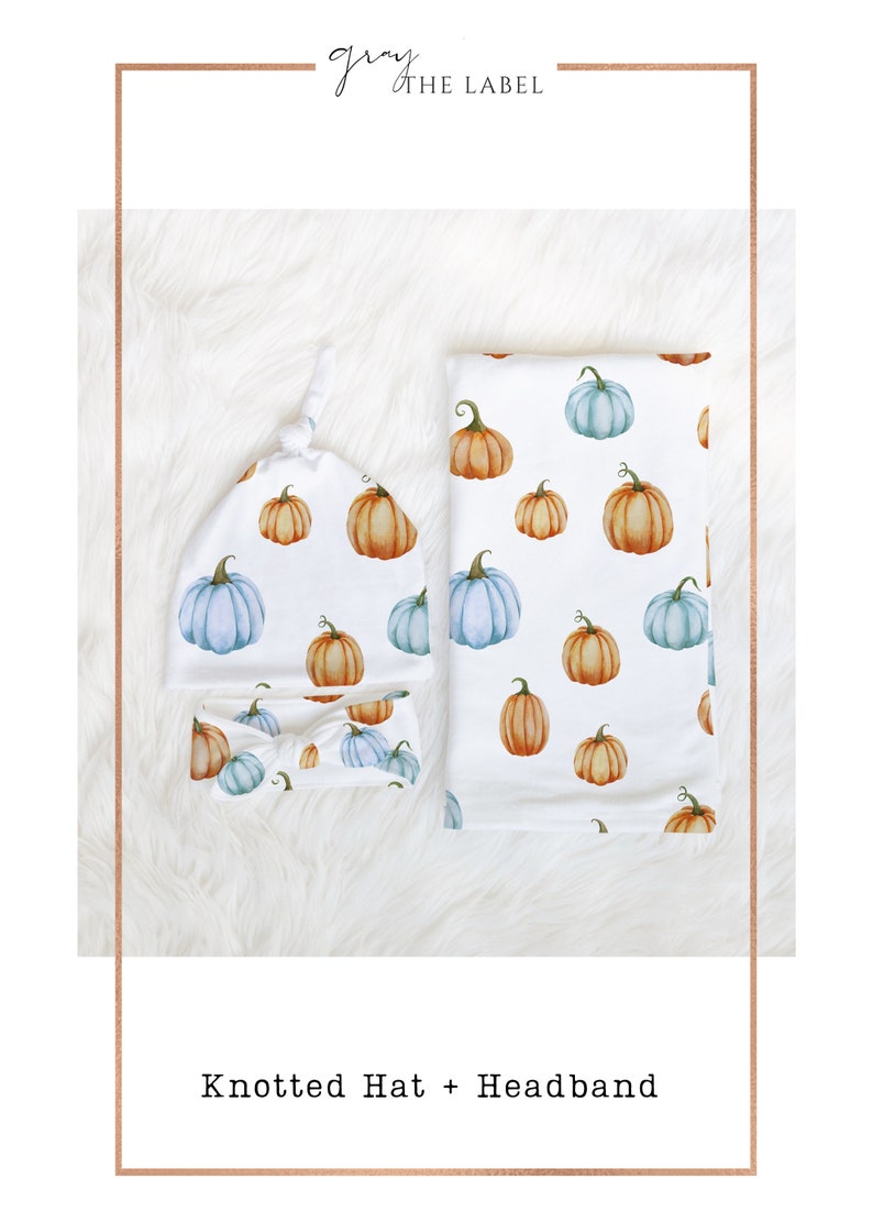 May include: A white baby set featuring a knotted hat, headband, and blanket, all adorned with watercolor pumpkins in shades of orange and blue. The set is designed for newborns and infants.