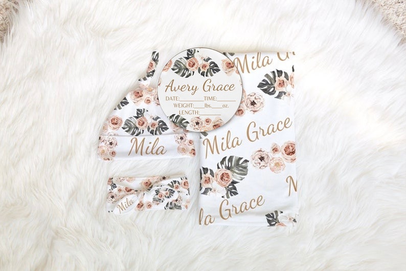 May include: A baby girl's nursery set with a floral print. The set includes a blanket, a hat, a headband, and a wooden plaque with the name "Avery Grace" and spaces to fill in the baby's birth information.
