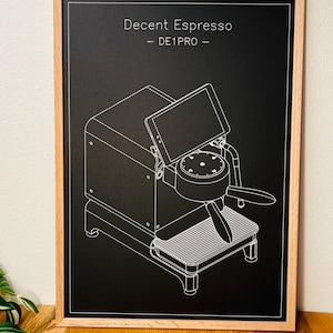 May include: Black and white line drawing of a Decent Espresso DE1PRO espresso machine, framed in wood. The image shows the machine's components, including the portafilter, water tank, and display screen. The text "Decent Espresso - DE1PRO -" is at the top.