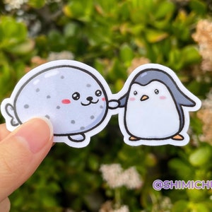 Pegatina brillante de foca y pingüino tomados de la mano