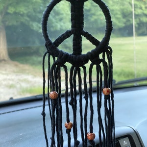 Peut inclure: Un attrape-r&ecirc;ves en macram&eacute; noir en forme de signe de paix avec des perles en bois suspendu &agrave; un r&eacute;troviseur.