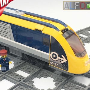 May include: A yellow and blue LEGO train with a black windshield and a gray stripe. The train has a number "60197" printed on the side. The train is on a gray LEGO track.