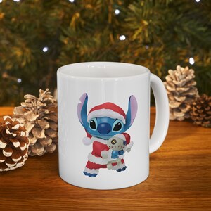 Puede incluir: Taza de cer&aacute;mica blanca con un personaje de dibujos animados azul y rojo que lleva un gorro de Pap&aacute; Noel y sostiene un juguete de peluche. El personaje es Stitch de la pel&iacute;cula de Disney Lilo & Stitch.