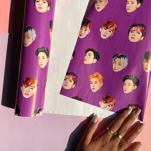 May include: Purple wrapping paper with a repeating pattern of men's faces. The faces are all different, but they all have the same style of hair and clothing.