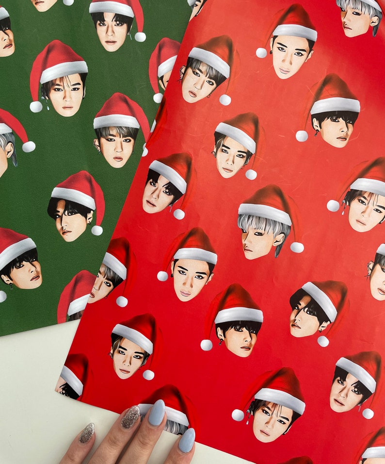 May include: Two sheets of wrapping paper with a repeating pattern of a person wearing a Santa hat. One sheet is red with white dots and the other is green with white dots.
