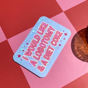 May include: A rectangular sticker with rounded corners, featuring the text "I WOULD LIKE A LOBOTOMY & A DIET COKE" in pink, outlined in white, on a light blue background. Small pink stars are scattered around the text. The sticker has a holographic, glittery finish.