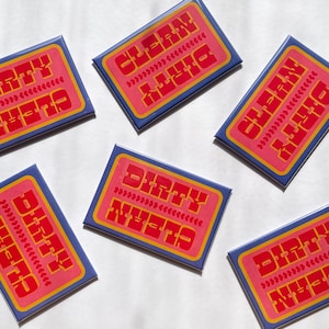 May include: Rectangular magnets with a retro design. Each magnet has a pink center with the words "DIRTY" and "CLEAN" in red, and "NEEDS" in yellow. The magnets are surrounded by a blue border.