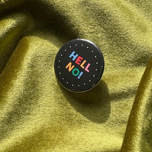 May include: A black button with white dots around the edge. The button says "HELL NO!" in colorful letters.