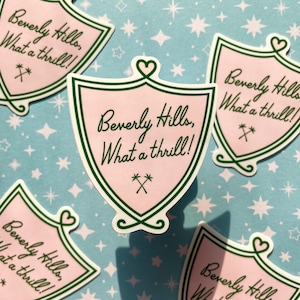 May include: Five pink and green shield-shaped stickers with the text "Beverly Hills, What a thrill!" on a blue background with white stars.