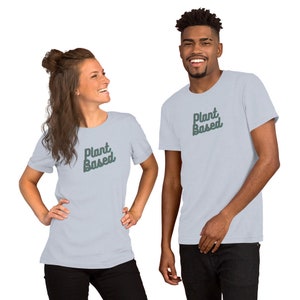 May include: Two people wearing light blue t-shirts with the text "Plant Based" in green lettering.