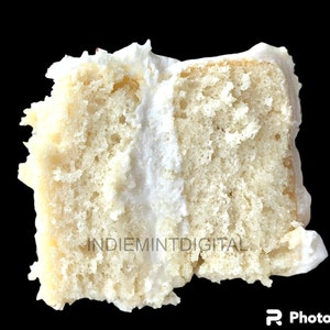 Puede incluir: Primer plano de un pastel blanco de dos capas con glaseado blanco. El pastel está cortado por la mitad y el glaseado es visible entre las capas.