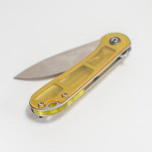May include: A yellow pocket knife with a silver blade. The knife is closed and has a textured handle.