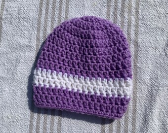 May include: Purple crocheted beanie with a white stripe.