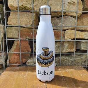 May include: White stainless steel water bottle featuring a black and gold snake design with the name "Jackson" printed on the front.