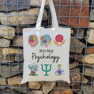 Puede incluir: Bolsa de tela blanca con un dise&ntilde;o de psicolog&iacute;a colorido. La bolsa presenta un cerebro, una pieza de rompecabezas, una mano sosteniendo un cerebro, un &aacute;rbol, un s&iacute;mbolo de psicolog&iacute;a y una bombilla. El texto "Mrs. May Psychology" est&aacute; impreso en la bolsa.