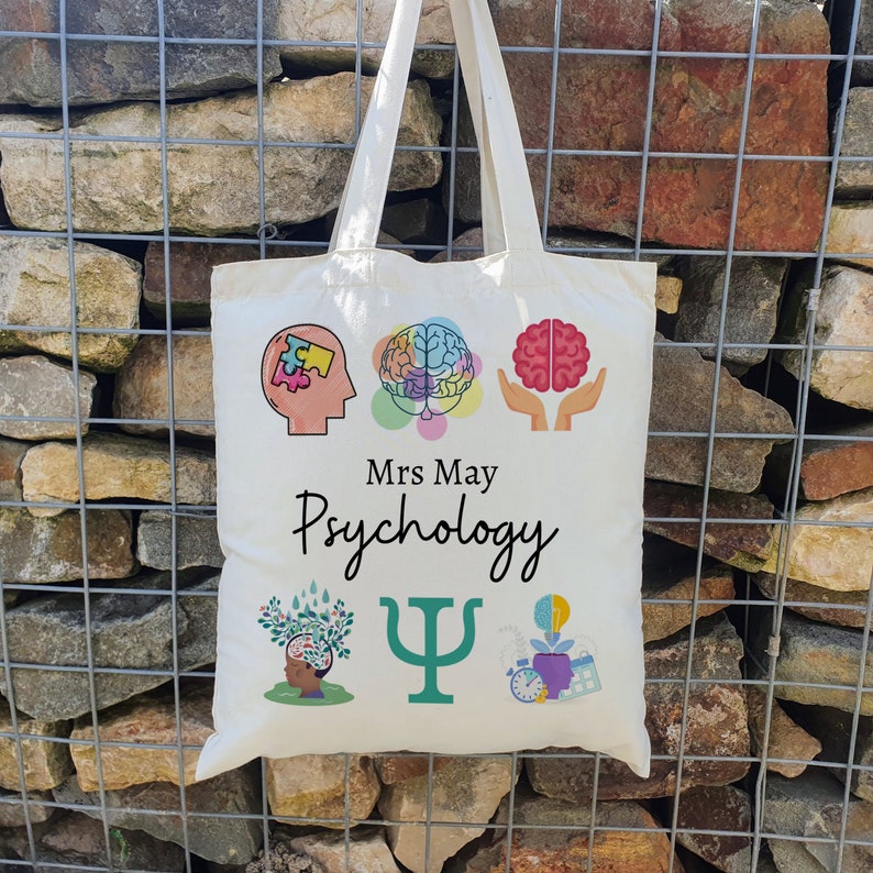 Puede incluir: Bolsa de tela blanca con un dise&ntilde;o de psicolog&iacute;a colorido. La bolsa presenta un cerebro, una pieza de rompecabezas, una mano sosteniendo un cerebro, un &aacute;rbol, un s&iacute;mbolo de psicolog&iacute;a y una bombilla. El texto "Mrs. May Psychology" est&aacute; impreso en la bolsa.