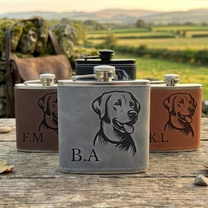 May include: Three stainless steel flasks wrapped in leather-like material in grey, dark brown, and light brown. Each flask features a laser-engraved portrait of a dog and custom initials: B.A on the grey, F.M on the dark brown, and K.L on the light brown.
